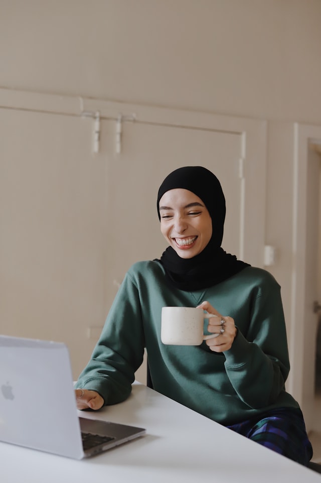 a young woman in hijab holding a mug 