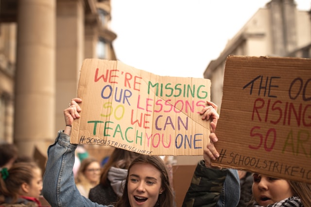 girl holding cardboard sign depicts how covid drives Gen Z to look for purpose