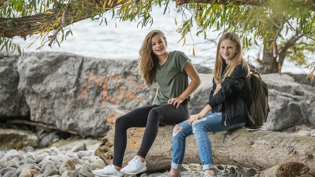Two teenage girls sitting on a log